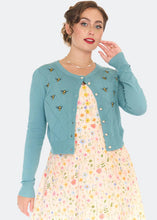 Load image into Gallery viewer, Woman wearing a teal cardigan with bee embellishments and a floral dress on a white background