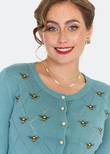 Load image into Gallery viewer, A woman wearing a teal blue knit cardigan sweater with embroidered bumblebees and pearl buttons, photographed against a clean white background.