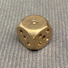 Load image into Gallery viewer, Gold metal die on a textured gray background