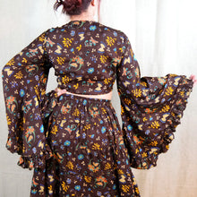 Load image into Gallery viewer, Person wearing a floral-patterned dress with long sleeves and a skirt.