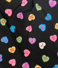 Load image into Gallery viewer, Black fabric with colorful heart-shaped candy text prints on a black background