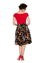 Load image into Gallery viewer, A woman shown from the back wearing a bright red short-sleeve top and a black pleated skirt with a detailed multicolor illustration print, paired with red high heels, against a plain white background.