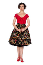 Load image into Gallery viewer, A woman modeling a retro-style two-piece outfit featuring a bright red short-sleeve top with a bow at the neckline and a black pleated skirt with a colorful vintage illustration print, paired with red heels, against a plain white background.