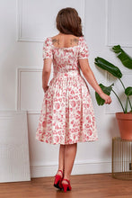 Load image into Gallery viewer, Woman wearing a floral dress standing in a room with a plant.