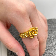 Load image into Gallery viewer, Gold rose-shaped ring on a person's finger with a neutral background