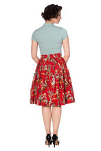 Load image into Gallery viewer, A woman shown from the back wearing a light sage green short-sleeve mock-neck top and a red high-waisted A-line skirt with a vintage circus or carnival print featuring clowns, elephants, and performers. She is wearing black high heels against a plain white background.