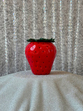 Load image into Gallery viewer, Red strawberry-shaped object on a textured surface with a patterned background
