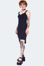 Load image into Gallery viewer, Person wearing a black dress with tattoos on arms and legs against a white background
