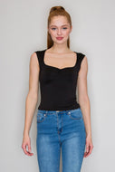 Woman wearing a black sleeveless top and blue jeans against a plain background