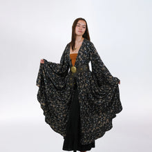 Load image into Gallery viewer, Woman wearing a long, dark floral-patterned coat on a white background
