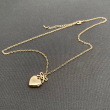 Load image into Gallery viewer, Gold heart-shaped locket necklace on a gray surface
