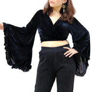 Person wearing a black velvet outfit with wide sleeves against a white background