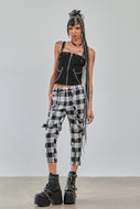 Person wearing a black sleeveless top and plaid pants with platform shoes on a plain background