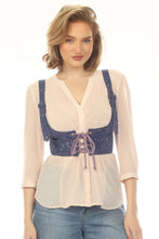 Load image into Gallery viewer, A woman modeling a cream-colored pleated blouse with a wide navy blue lace-up corset-style waist belt and matching shoulder straps, paired with blue jeans against a white studio background.
