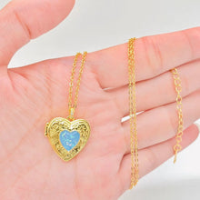 Load image into Gallery viewer, Gold heart-shaped locket with blue heart design on a hand
