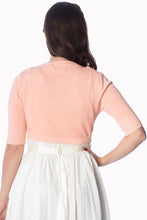 Load image into Gallery viewer, A woman shown from the back wearing a light peach-pink short-sleeve knit top and a white skirt, against a plain white background.
