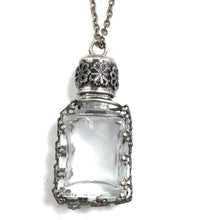 Load image into Gallery viewer, A vintage-style silver-toned pendant necklace featuring a clear glass vial with an ornate filigree cap and beaded border, shown on a white background.

