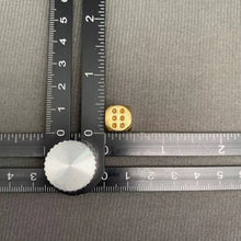 Load image into Gallery viewer, Two dice, one silver and one gold, on a textured gray surface with a ruler for scale.
