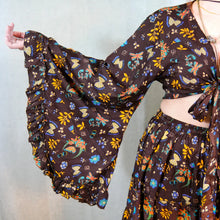 Load image into Gallery viewer, Person wearing a brown floral-patterned outfit with long sleeves and a skirt.
