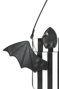 Black bat-shaped strap accessory on a clear handbag with black and white striped pattern.