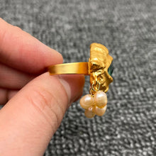 Load image into Gallery viewer, Gold ring with pearl pendants held by a hand against a gray background
