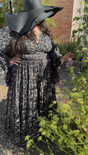 Load image into Gallery viewer, Person wearing a black and white patterned dress with a wide-brimmed hat in an outdoor setting.
