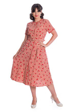 Load image into Gallery viewer, A woman modeling a short-sleeve red and white gingham A-line dress with a red heart print, paired with white heels, against a plain white background.
