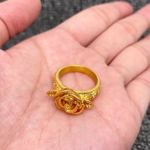 Load image into Gallery viewer, Gold ring with floral design held in a hand against a blurred background
