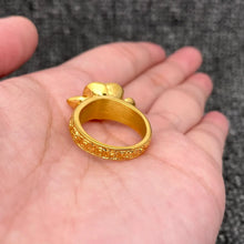 Load image into Gallery viewer, Gold ring with intricate design held in a hand against a gray pavement background
