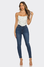 Load image into Gallery viewer, Woman wearing a white floral top and blue jeans on a white background
