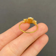 Load image into Gallery viewer, Gold ring held on a finger against a dark background
