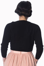 Load image into Gallery viewer, Back view of a person wearing a black long-sleeve cropped top and a light pink pleated skirt against a plain white background.

