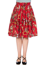 Load image into Gallery viewer, A red pleated A-line skirt with a detailed vintage-style western illustration print, shown on a model from the waist down wearing black strappy heels against a white background.
