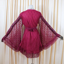 Load image into Gallery viewer, A magenta lace kimono-style cover-up dress displayed on a mannequin, featuring wide bell sleeves and a tie belt at the waist, set against a cream-colored curtain backdrop.
