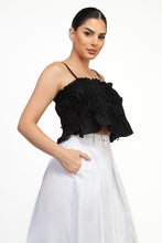 Load image into Gallery viewer, Woman wearing a black ruffled top and white pants on a white background
