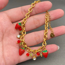 Load image into Gallery viewer, Gold chain bracelet with strawberry charms held in a hand against a gray background
