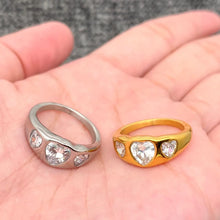 Load image into Gallery viewer, Two rings, one silver and one gold, held in a hand with a neutral background.
